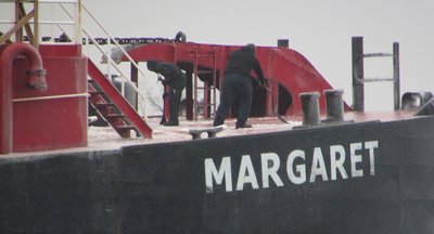 I heard scraping coming from the bow of the barge and when I zoomed in, discovered two of the crew scraping ice from the deck.  Their previous port was Calcite (Rogers City).