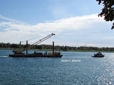 A wide-angle look taking in tug, tow line, and work barge.